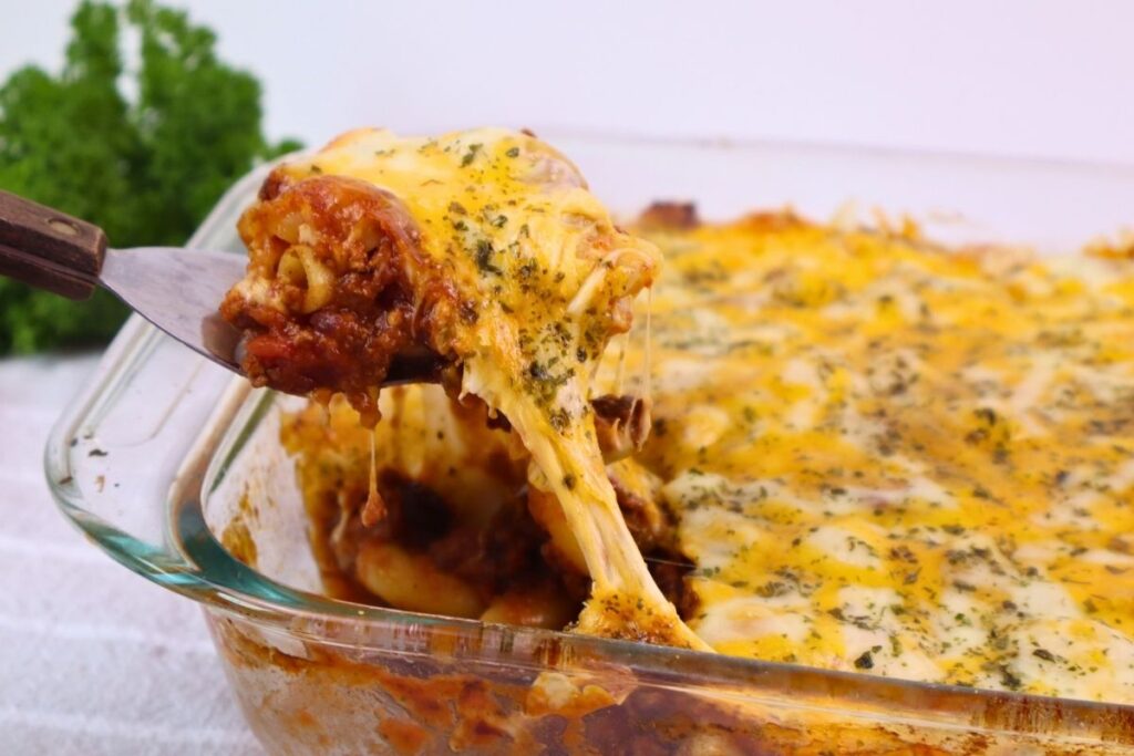 Easy Baked Gluten-Free Chili Mac 4 Spoon lifting a cheesy scoop of gluten-free chili mac from the baking dish