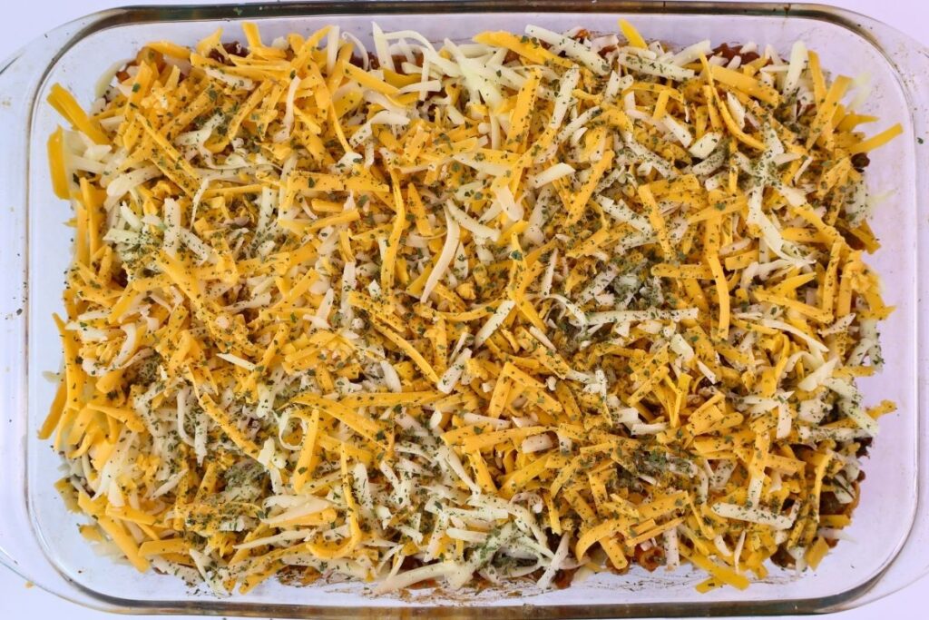 Easy Baked Gluten-Free Chili Mac 8 Gluten-free chili mac topped with shredded cheddar, mozzarella, and herbs before baking