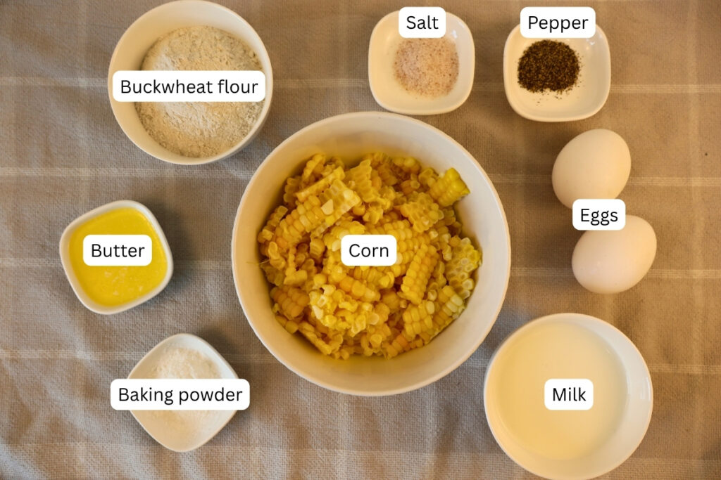 Gluten-Free Pennsylvania Dutch Corn Fritters 6 Ingredients for gluten-free Pennsylvania Dutch corn fritters, including buckwheat flour, corn, eggs, butter, and milk in labeled bowls