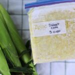 How to Freeze Sweet Corn: A Step-by-Step Preservation Guide 22 Fresh sweet corn ears in the husk with a frozen bag of sweet corn for step-by-step instructions of how to freeze sweet corn.