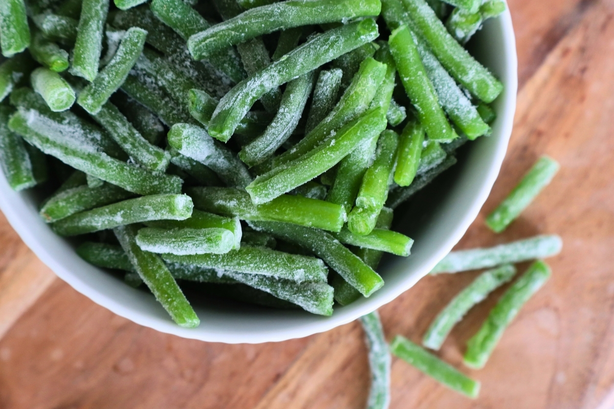White bowl of frozen green beans with frost, seen from above